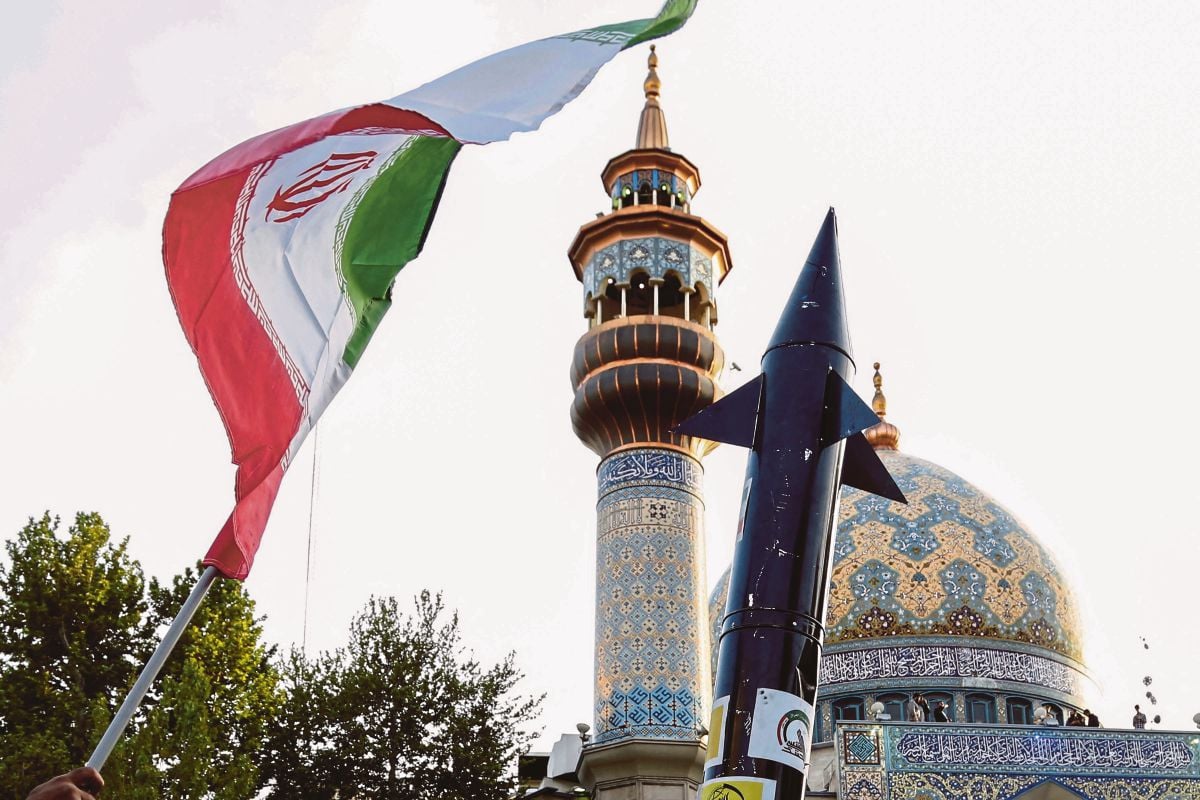 IRAN mengangkat bendera dan mock up peluru berpandu semasa perayaan di dataran Palestin di tengah Tehran. FOTO AFP