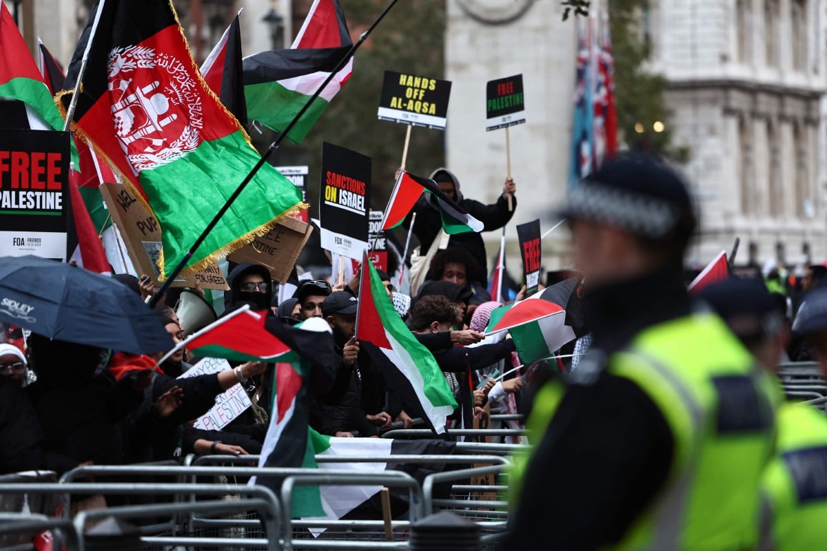 Penunjuk perasaan memegang sepanduk dan mengibarkan bendera Palestin di Downing Street selepas mengambil bahagian dalam 'March For Palestine' di London pada 28 Oktober 2023. FOTO AFP