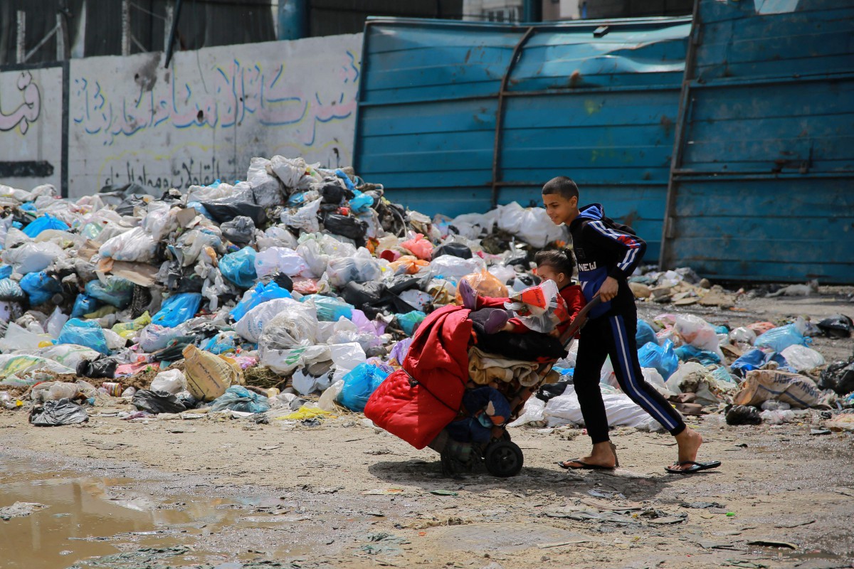 Seorang kanak-kanak berjalan melepasi timbunan sampah rumah di sebuah jalan di Kota Gaza pada 28 Mac 2024. FOTO AFP
