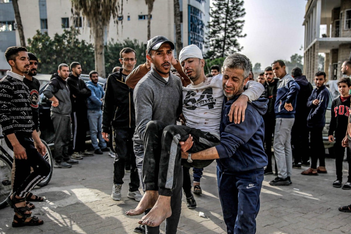 Dua lelaki membawa seorang lelaki yang cedera di luar hospital Ahli Arab di Bandar Gaza pada 27 Mac 2024. Foto AFP