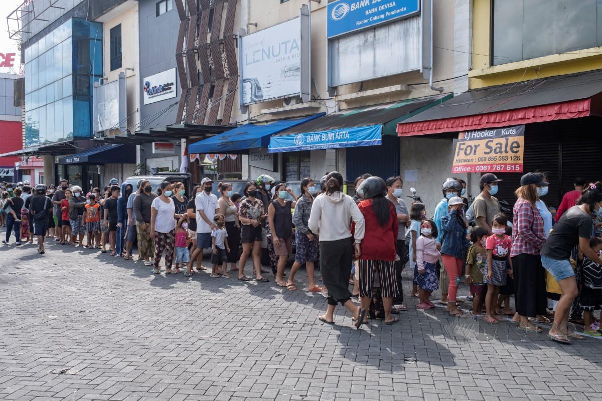 Orang ramai beratur untuk mendapatkan makanan percuma di Kuta, Bali, Indonesia. - FOTO EPA