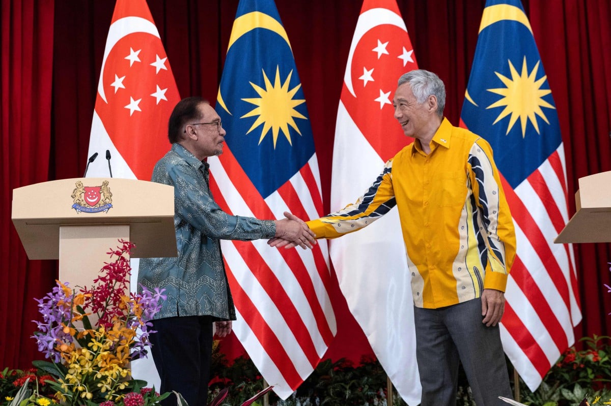 Perdana Menteri Malaysia, Datuk Seri Anwar Ibrahim berjabat tangan dengan Perdana Menteri Singapura, Lee Hsien Loong. - FOTO AFP