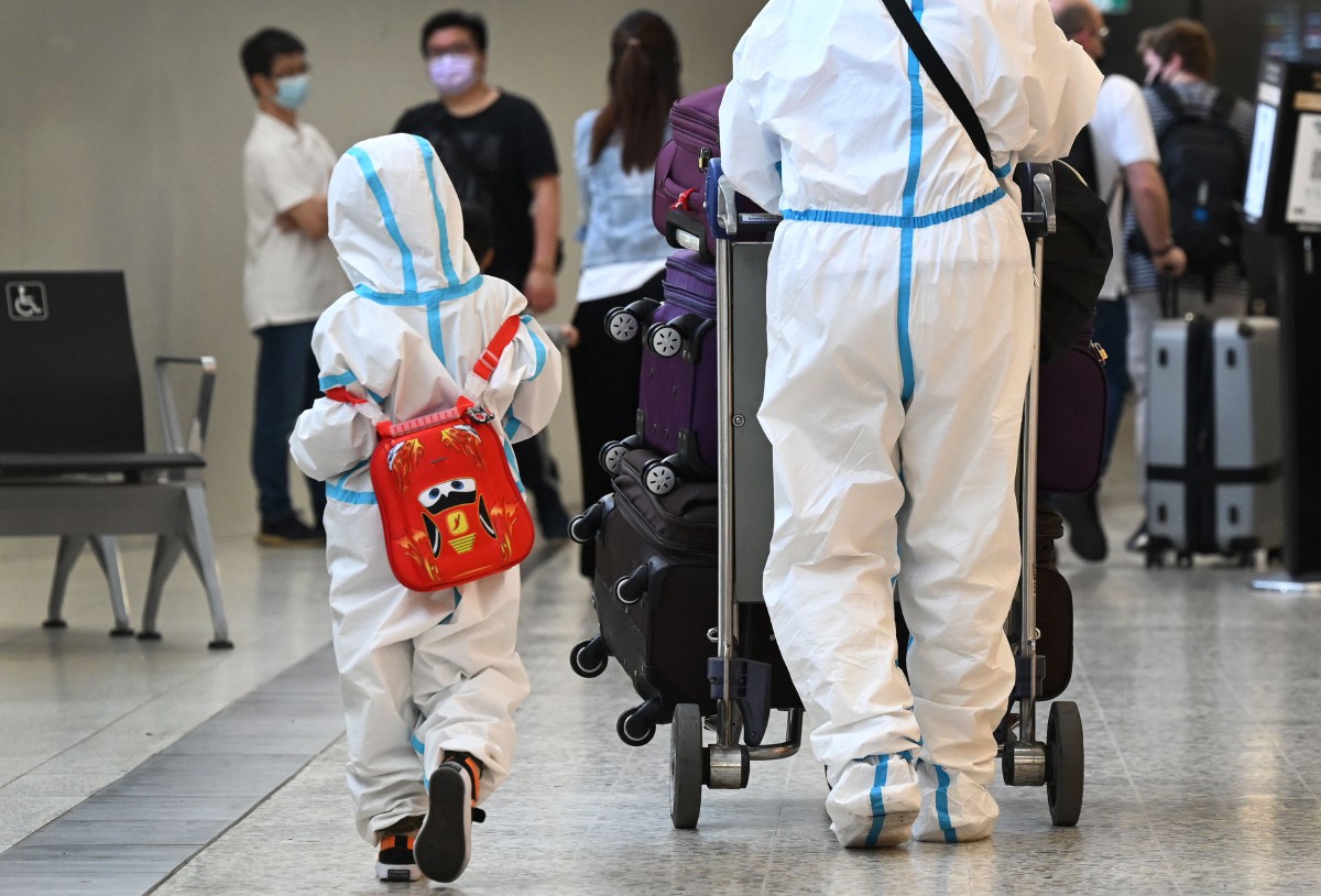 Pelawat mengenakan pakaian perlindungan diri tiba di Lapangan Terbang Tullamarine di Melbourne. - AFP