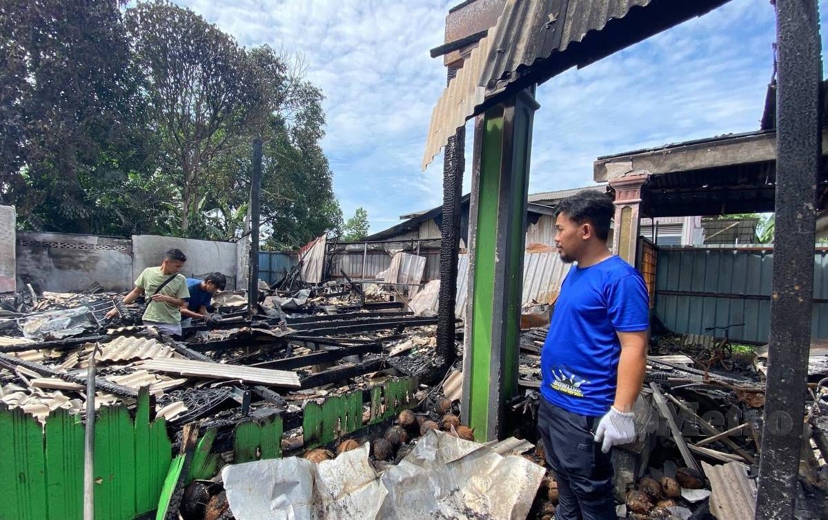 FIRDAUS (berbaju biru) menunjukkan kediaman keluarganya yang terbakar di Kampung Aman terbakar awal pagi tadi.FOTO Hazira Ahmad Zaidi
