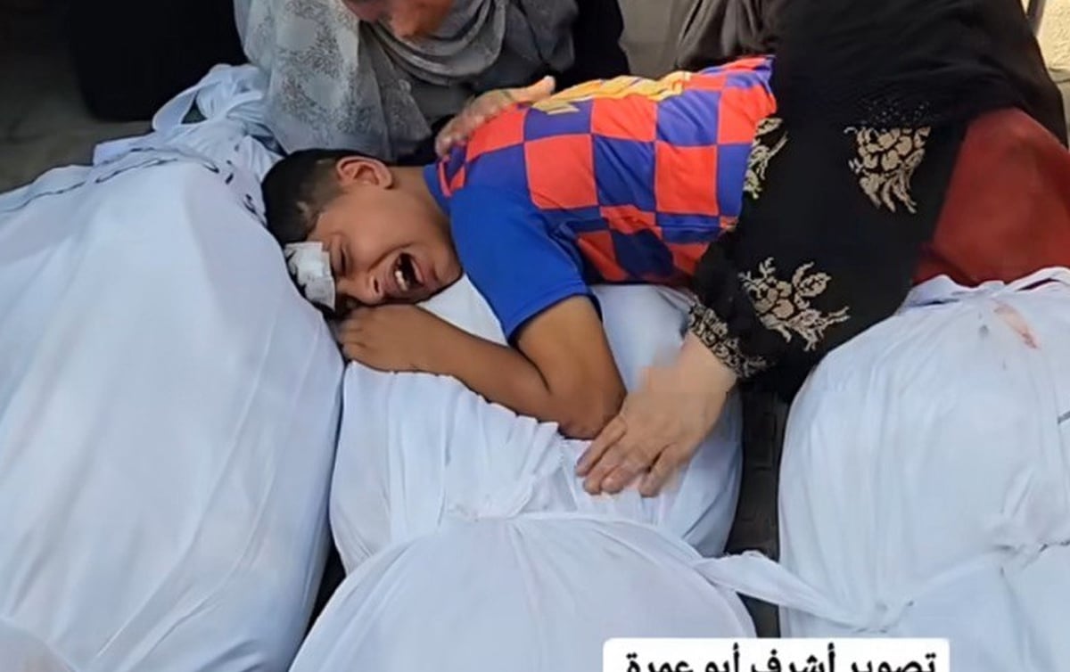 KANAK-KANAK lelaki itu memeluk jasad ibunya ketika memberikan penghormatan terakhir. FOTO tangkap layar video Ashraf Amra