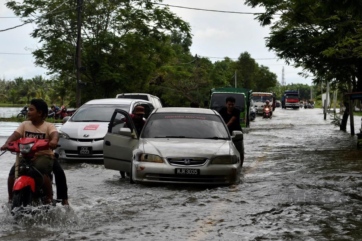 Sebahagian kenderaan mengharungi air yang melimpahi Jalan utama  di Kampung Sri Sentosa berikutan banjir kilat susulan hujan lebat yang berlaku sejak pagi tadi  ketika tinjauan hari ini. FOTO  NIK ABDULLAH NIK OMAR
