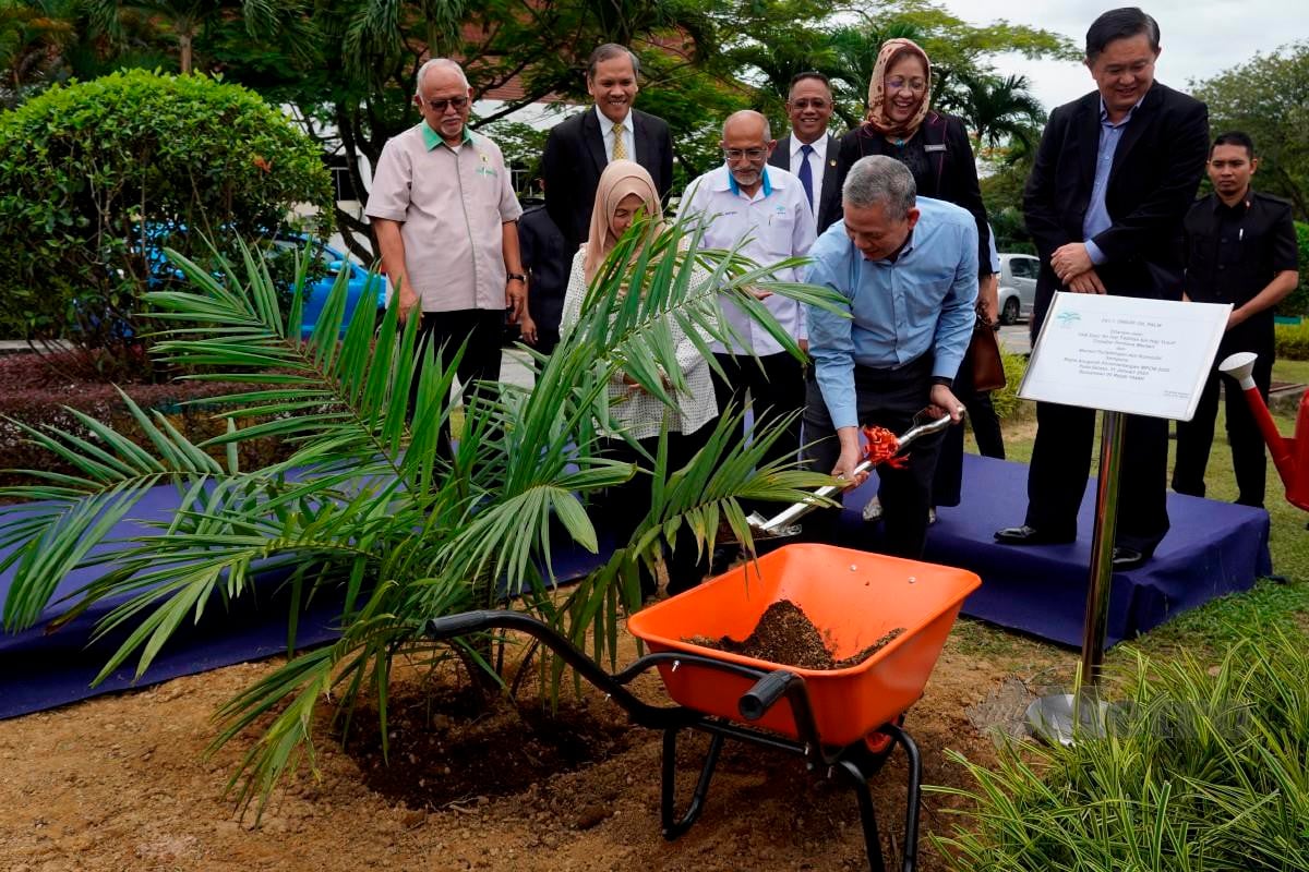 Fadillah meletakkan tanah pada anak pokok sawit hibrid yang ditanam sempena Majlis Anugerah Kecemerlangan MPOB  2022. - FOTO NSTP