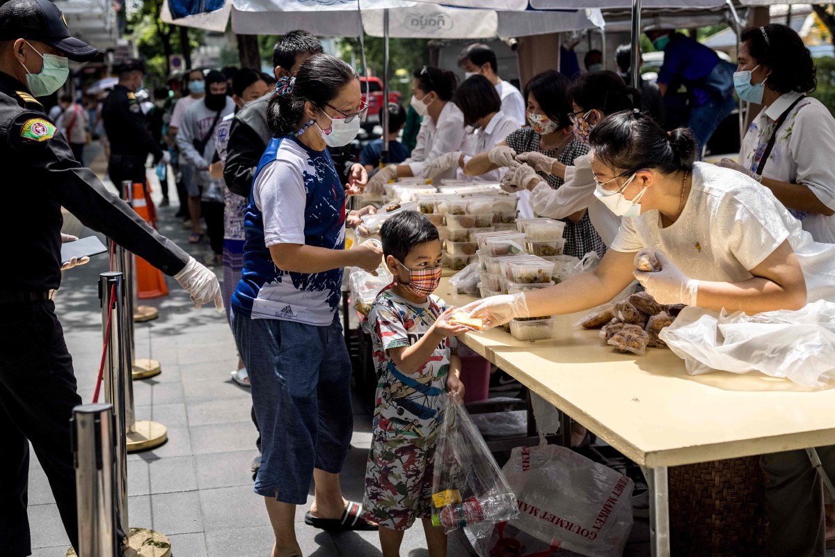 Sukarelawan membantu mengagihkan makanan kepada orang awam di Bangkok. - FOTO AFP