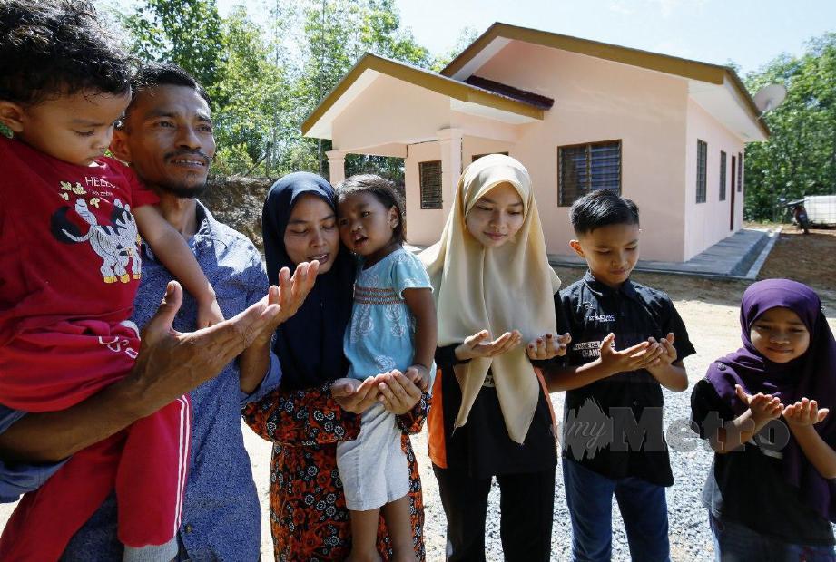 ABDULLAH (kiri) membaca doa sambil diaminkan oleh  isteri, Ruziah (dua dari kiri) serta anak-anak di hadapan rumah mereka yang dibina oleh Pusat Zakat Kedah. FOTO Amran Hamid