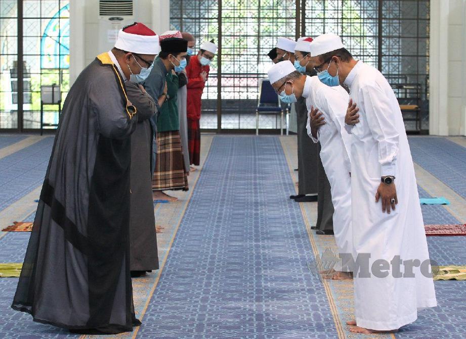 DATUK Mohd Yusop Husin (kanan) dan jemaah yang hadir meletakkan tangan kanan ke dada dan menundukkan kepala tanda hormat selepas solat jumaat di Masjid Sultan Azlan Shah. FOTO Sharul Hafiz Zam