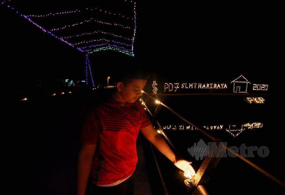 NAJMI, membetulkan pelita yang dipasang di pintu masuk ke Kampung Pida 7, Jerlun  untuk memeriahkan suasana hari raya. FOTO Amran Hamid