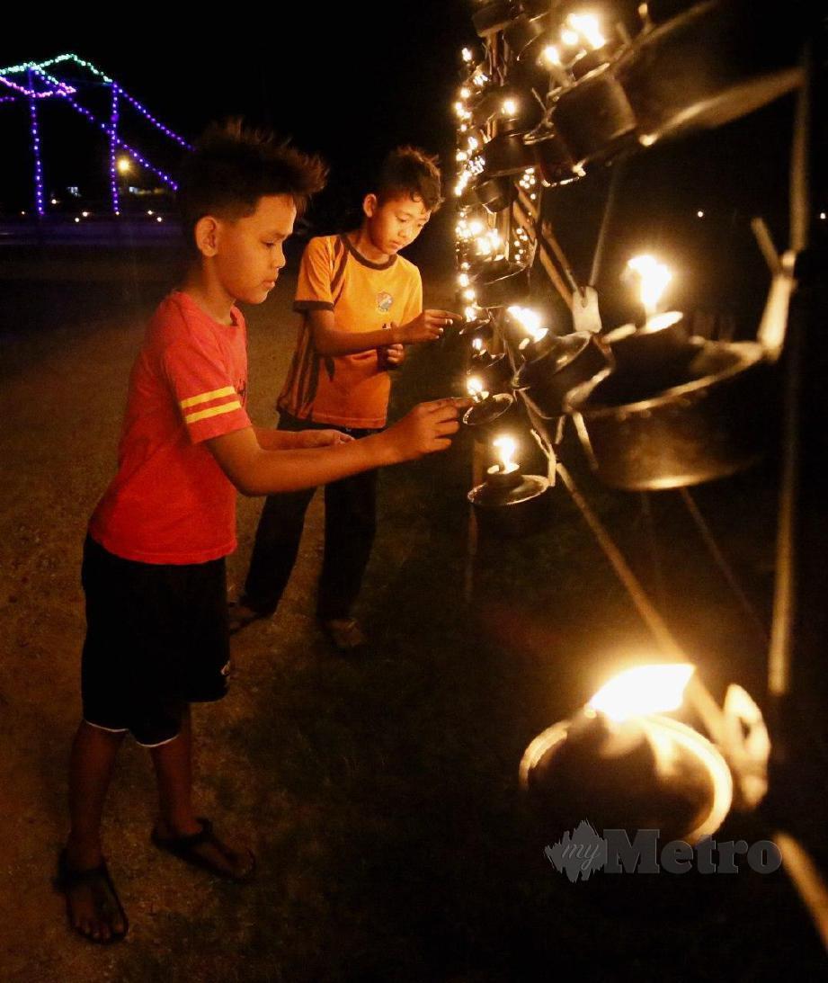 SERAMAI 20 anak muda dari pelbagai peringkat usia bersama-sama bergotong-royong memasang pelita dan lampu hiasan untuk menyambut minggu terakhir Ramadan dan malam tujuh likur. FOTO Amran Hamid