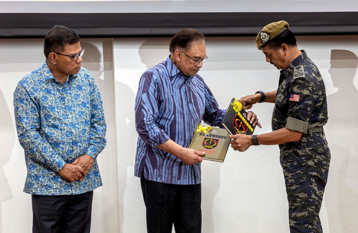 IPOH, 4 Mei -- Perdana Menteri Datuk Seri Anwar Ibrahim (tengah) menerima buku 69 Komando dari Ketua Polis Negara Tan Sri Razarudin Husain (kanan) pada Majlis Ramah Mesra Raya MADANI bersama Warga Unit 69 Komando, Pasukan Gerak Khas, Ulu Kinta di Pusat Latihan Unit 69 Komando hari ini.