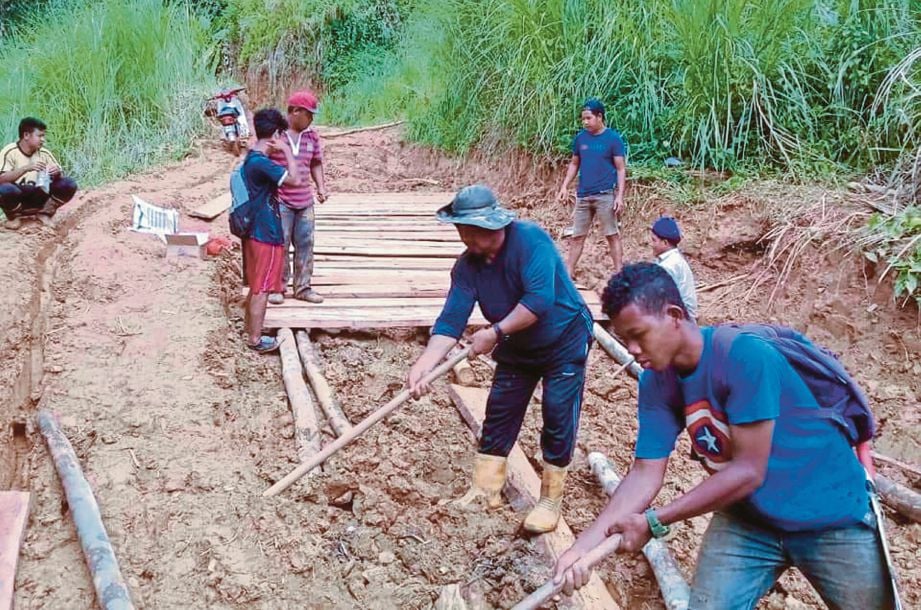 PENDUDUK Orang Asli kelihatan bergotong royong membina rakit kayu di Pos Bihai yang berlumpur bagi memudahkan anak-anak mereka pergi ke SMKTIP1 Gua Musang hari ini. FOTO Bernama