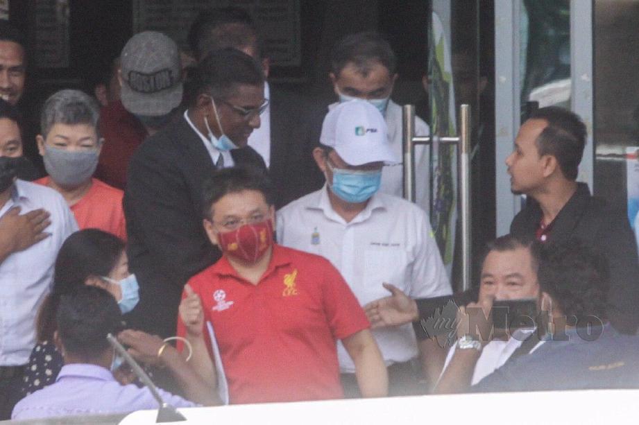 JEFFREY Chew Gim Eam (baju merah) diiringi, Chow Kon Yeow (bertopi putih) keluar dari bangunan Ibu Pejabat SPRM Pulau Pinang, Jalan Sultan Ahmad Shah di sini. FOTO Danial Saad