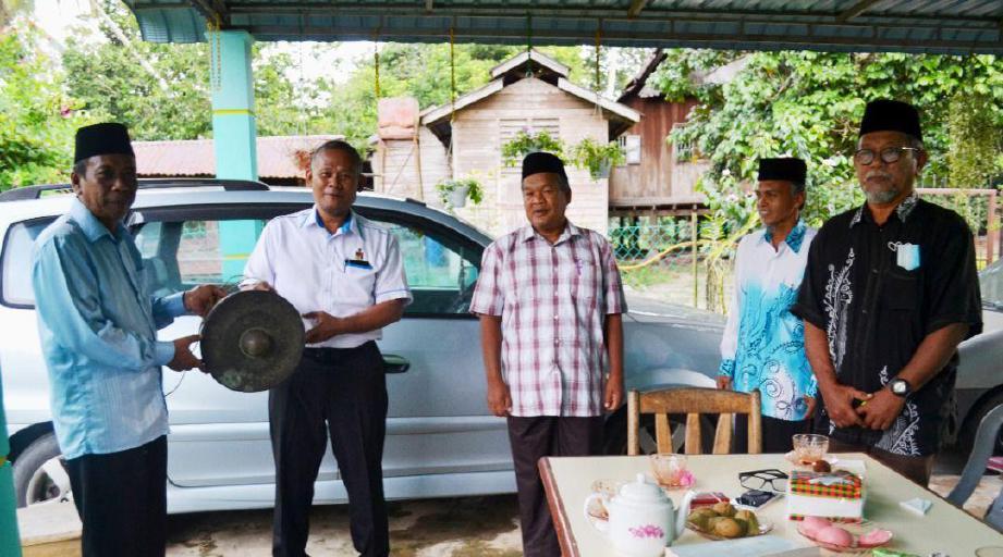 DR Shamsuddin Ahmad (dua dari kiri) menerima tetawak (gong) daripada Mohammad Ariff Sidek (kiri) di Balai Penghulu Luak Inas, Kuala Pilah. FOTO ihsan LMNS