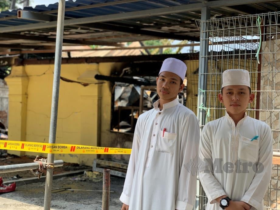 MOHD Haziq Abdul Kudus dan Muhamad Muzakir Ehsan Zulkifli di hadapan bangunan stor yang menyimpan barang masakan dan keperluan pelajar yang terbakar dalam kejadian tengah malam tadi. FOTO Noor Hidayah Tanzizi