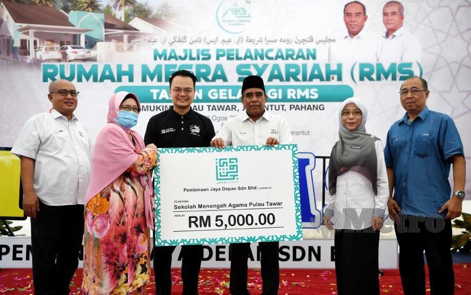 ABDUL Rahim (tiga dari kanan) menyampaikan sumbangan kepada Sekolah Menengah Agama Pulau Tawar yang diwakili Pengetuanya Saniah Muhammad pada majlis pelancaran Rumah Mesra Syariah Mukim Pulau Tawar. FOTO BERNAMA