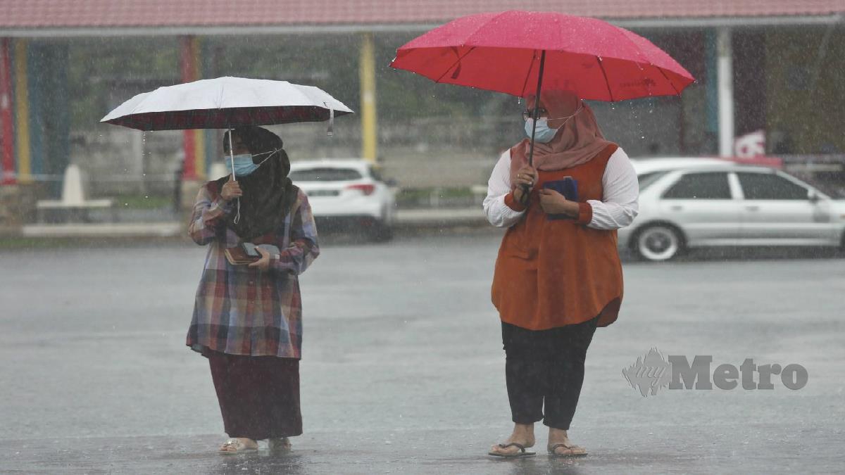 KELIHATAN orang ramai berjalan menggunakan payung meredah hujan lebat di Taman Syahbandar, Kuala Terengganu semalam. FOTO GHAZALI KORI