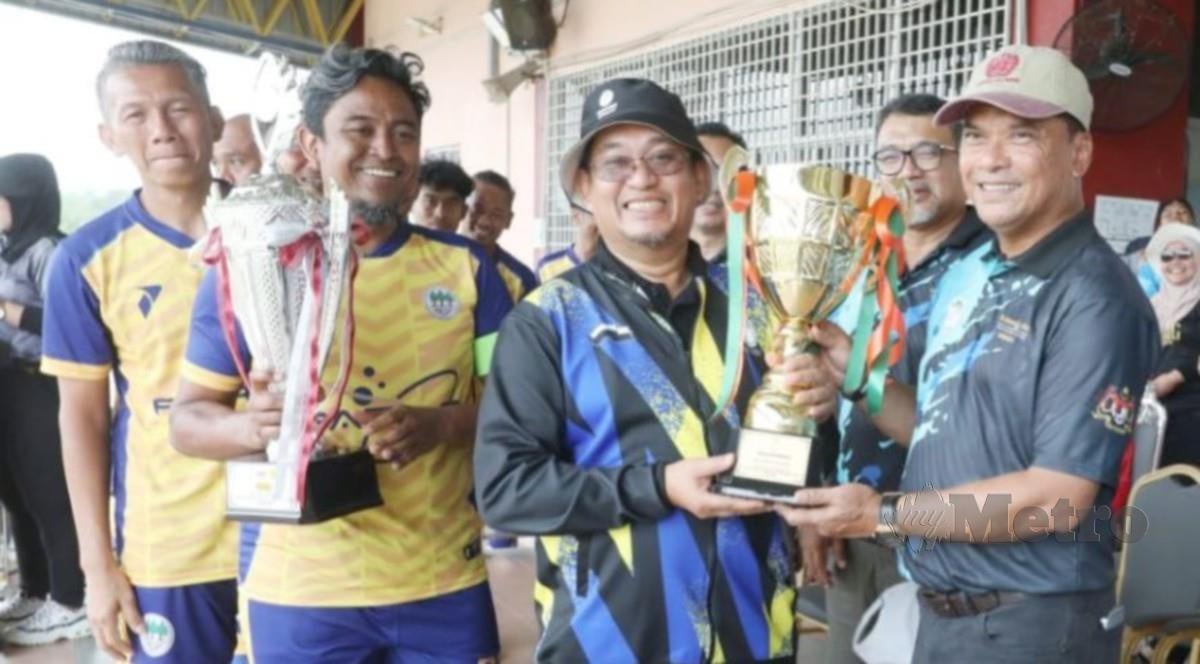 MOHD Ridza (kanan) menyampaikan piala kepada Roslan Rani selepas JPNP muncul juara Kejohanan Bolasepak Piala KPPSM 2024. FOTO MOHD RAFI MAMAT