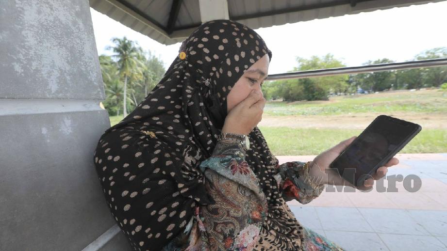 Zarina sebak menatap gambar Allahyarham Muhamad Hafiz yang meninggal dunia di HSNZ Kuala Terengganu selepas disyaki dijangkiti kencing tikus. Foto Mohd Rafi Mamat