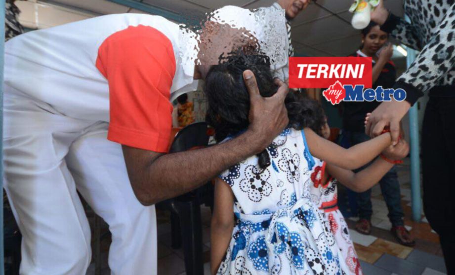 AHMAD bukan nama sebenar) mencium cucù perempuannya di Program Jalinan Kasih sambutan Aidilfitri di Penjara Reman Pulau Pinang. FOTO Shahnaz Fazlie Shahrizal 