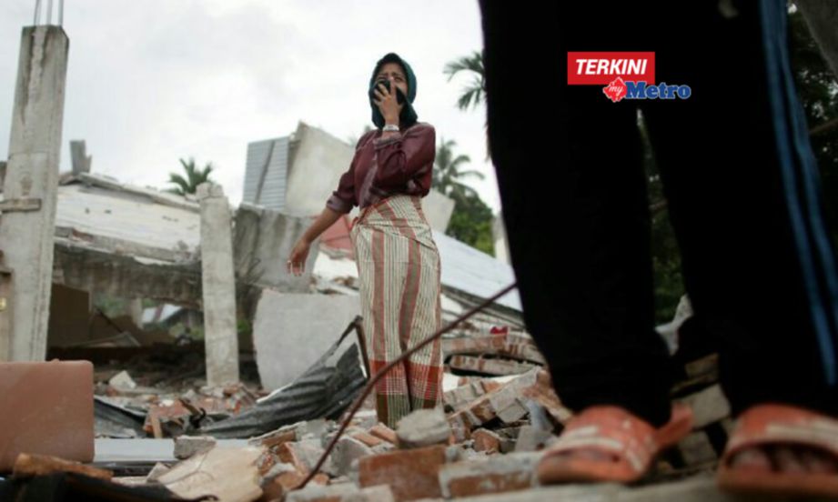 SAPRINA Rajali, 30, sebak ketika menceritakan perihal ibunya yang dihempap lantai konkrit ketika kejadian gempa. Dia berdiri di depan rumahnya yang musnah akibat gempa bumi di Kampung Teupin Peuraho, Meurudu, Banda Aceh . FOTO Aizuddin Saad 
