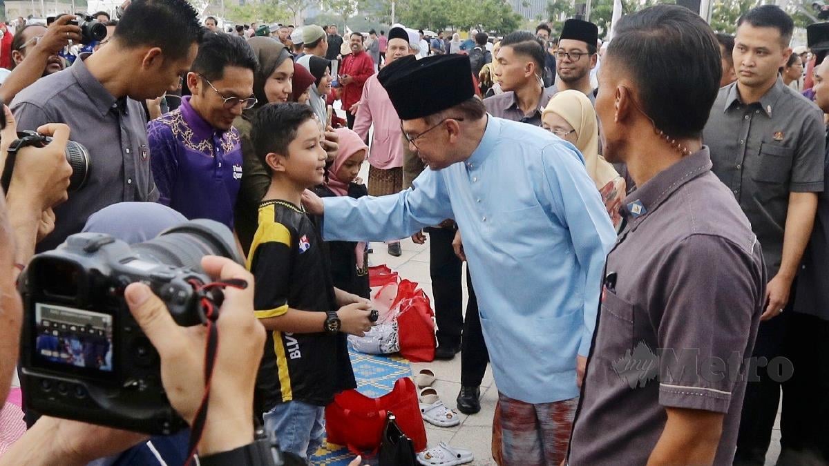 ANWAR berbual dengan seorang kanak-kanak ketika Majlis Iftar Madani (MIM) di Putrajaya. FOTO Mohd Fadli Hamzah