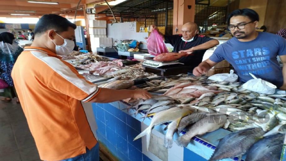 MOHD Saifulddin melayan pelanggan di gerai ikannya di Pasar Bukit Besar. FOTO Ahmad Rabiul Zulkifli. 