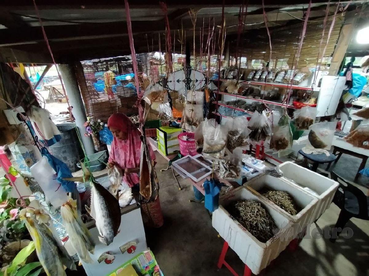 WAN Sapiah memeriksa  ikan kering yang elok untuk dijual digerai miliknya. FOTO NIK ABDULLAH NIK OMAR