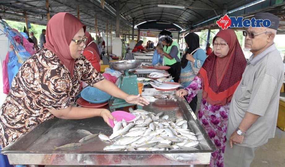 PENIAGA ikan melayan pelanggannnya yang membeli ikan di Pasar Seberang Kota, Kuala Kedah.  FOTO Sharul Hafiz Zam