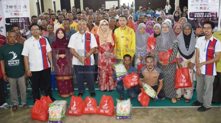KAMARUDDIN (empat dari kiri) bergambar bersama golongan asnaf yang menerima sumbangan daripada Yayasan Ikhlas di Dewan Sivik Kampung Seberang Pintasan, Dungun, hari ini. FOTO Rosli Ilham.