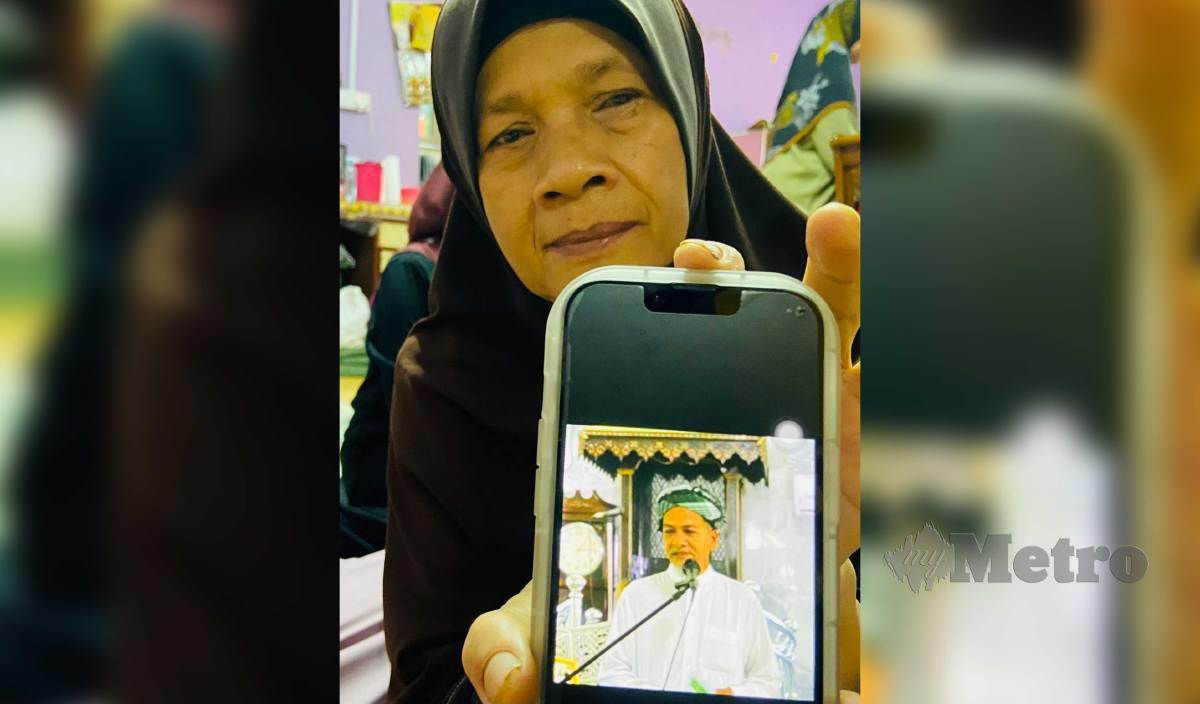 ROBIAH menunjukkan gambar arwah suaminya, Mohd Zamai @ Suhaimi Ibrahim yang meninggal dunia selepas selesai membacakan khutbah dan solat Jumaat petang semalam ketika ditemui di rumahnya di Kampung Mahligai. FOTO Hazira Ahmad Zaidi