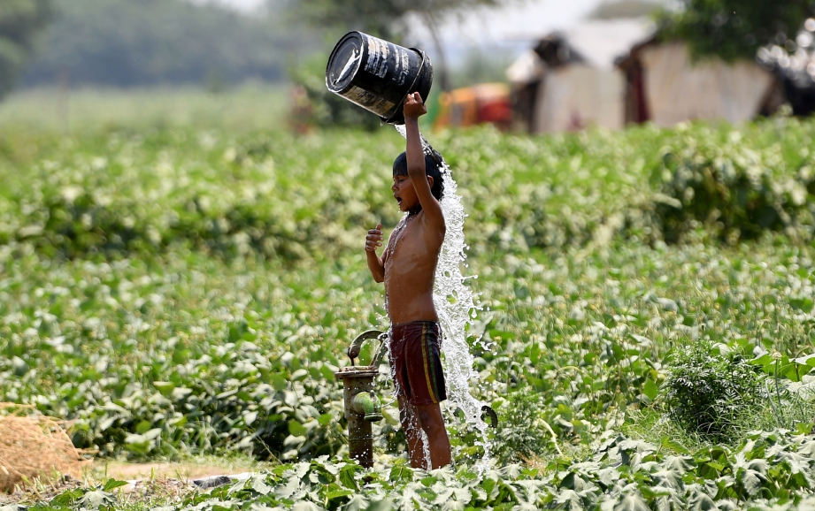 SEORANG budak india cuba menyejukkan diri setelah India dilanda gelombang panas melebihi 50 darjah Celsius. FOTO AFP.