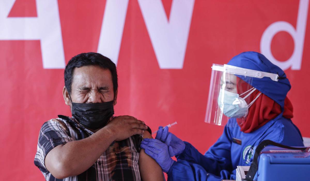 REAKSI seorang pekerja sebaik sahaja disuntik vaksin AstraZeneca oleh petugas kesihatan semasa program vaksinasi untuk pemandu di stesen bas Kampung Rambutan, Jakarta. FOTO EPA