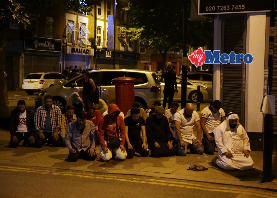 Sekumpulan umat Islam menunaikan solat di laluan pejalan kaki di Finsbury Park selepas insiden serangan. FOTO AFP