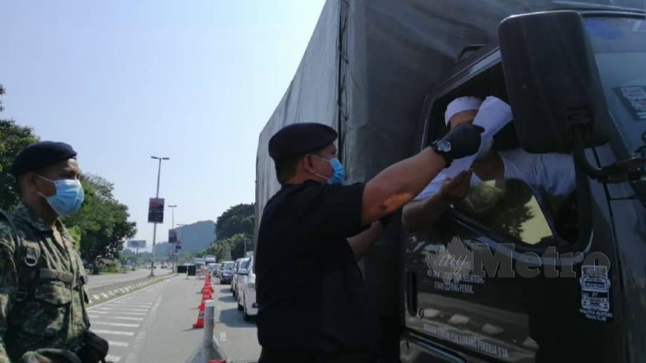 A Asmadi melakukan pemeriksaan terhadap beberapa kenderaan di Sekatan Jalan Raya (SJR) di Jalan Kuala Kangsar. FOTO Balqis Jazimah Zahari. 