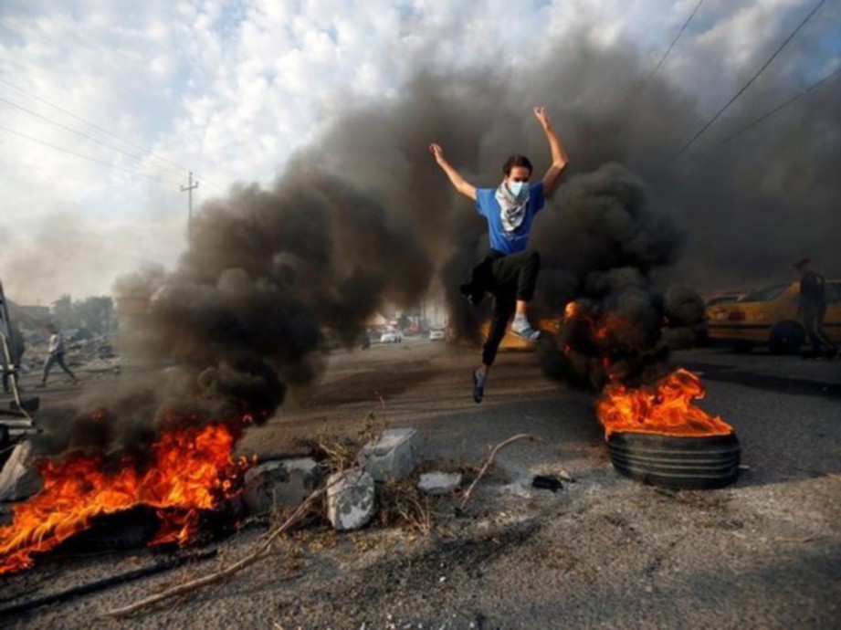 PENUNJUK perasaan melompat  berhampiran tayar terbakar di Basra, Iraq.