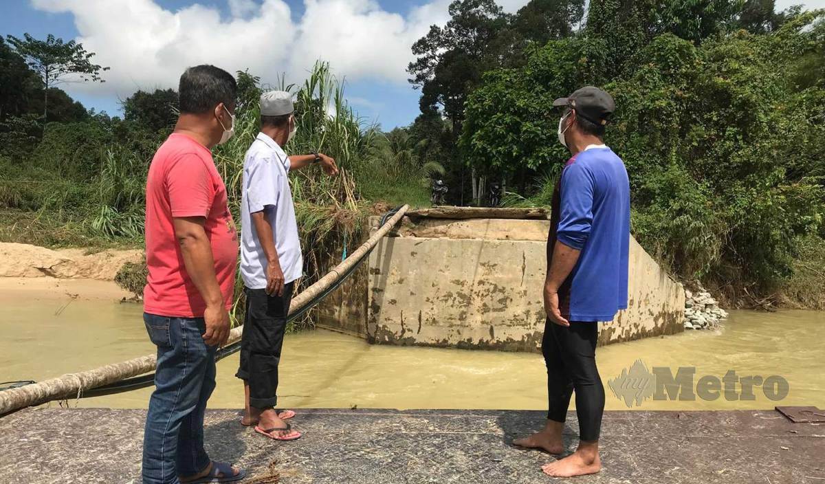 PENDUDUK kampung melihat keadaan sebahagian jambatan besi Kampung Temalir Lama yang runtuh susulan  limpahan air Sungai Pahi selain rempuhan sisa-sisa kayu yang dibawa bersama arus deras. FOTO Hazira Ahmad Zaidi