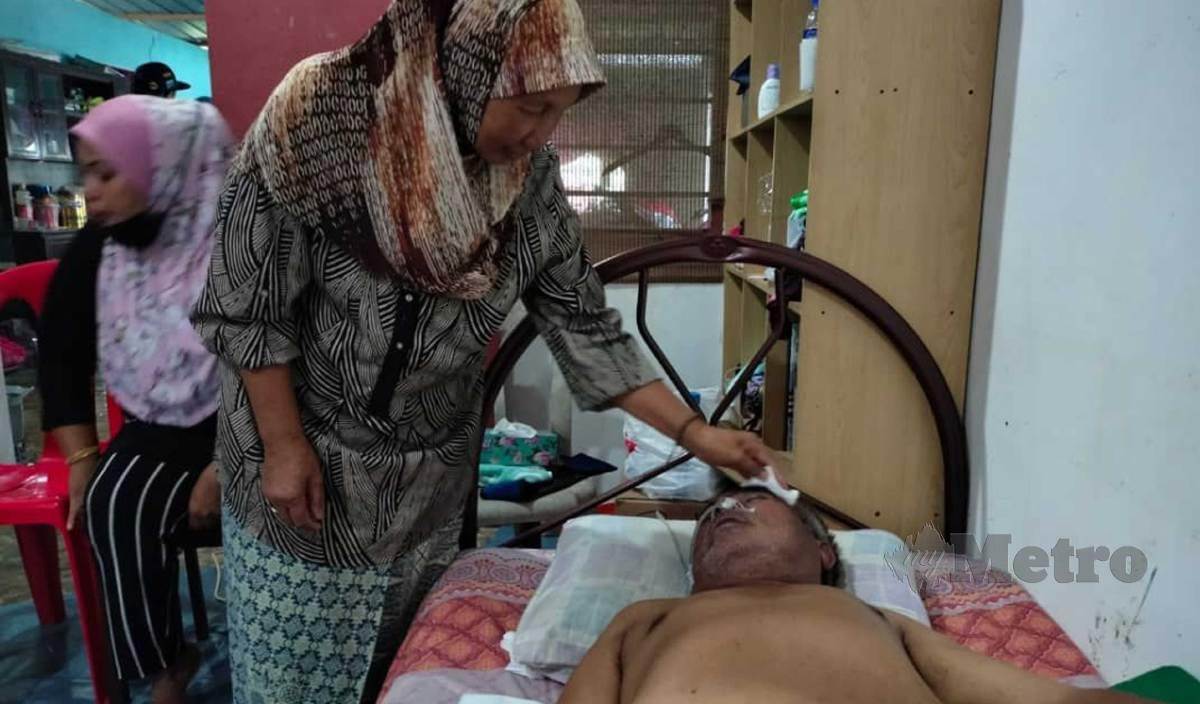 KAMARIAH menjaga suami, Abu Hasan yang terlantar akibat serangan strok di rumah mereka di Desa Kasih Parit 8 1/2 Barat. FOTO Amirul Aiman Hamsuddin