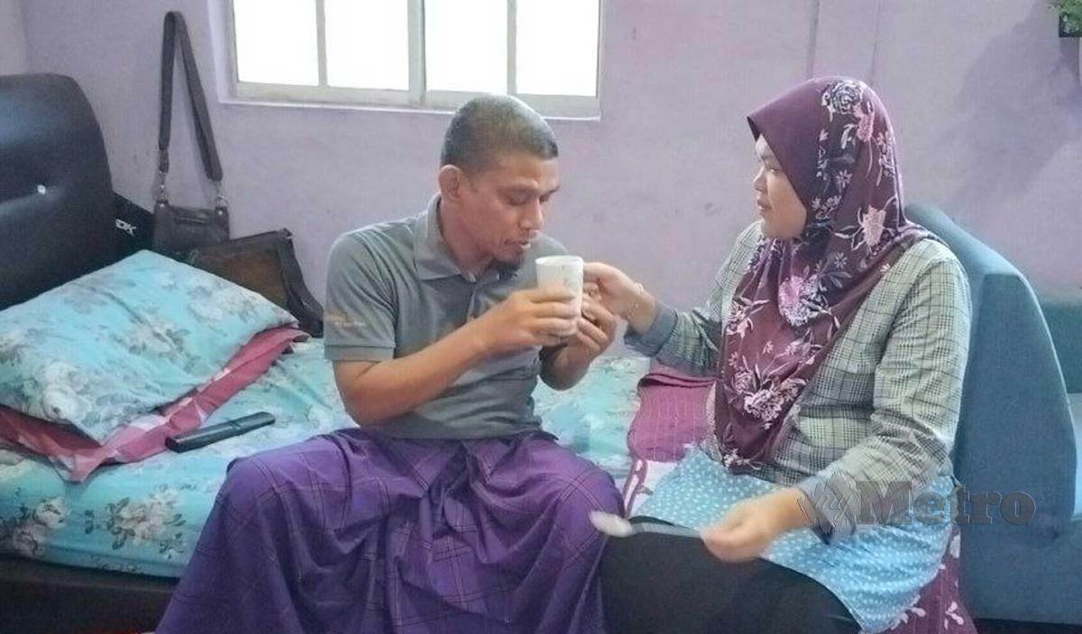 RAFIDAH (kanan) memberi susu formula khas kepada suaminya, Mohamad Idris yang menghidap barah usus tahap tiga sejak Ogos tahun lalu. FOTO Zuliaty Zulkiffli