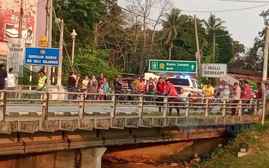 ORANG ramai menyaksikan kerja membuka semula laluan di jambatan menjadi sempadan daerah Muallim, Perak  dan Hulu Bernam, Selangor sedang dibuka semula, hari ini. FOTO ihsan pembaca. 