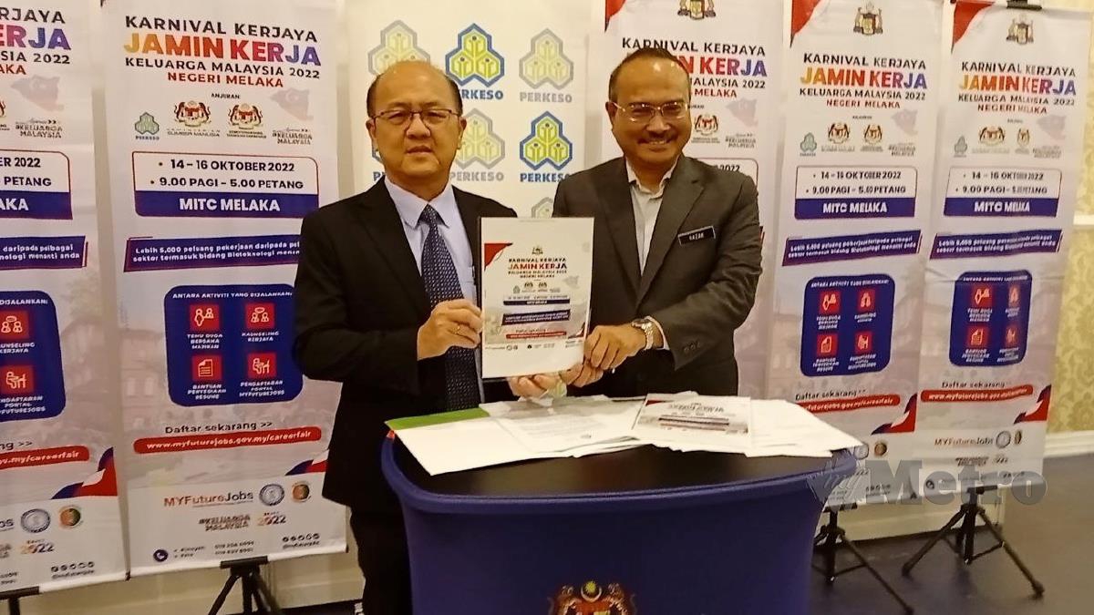 Ngwe (kiri) dan Abdul Razak menunjukkan poster Karnival Kerjaya Jamin Kerja Keluarga Malaysia 2022 peringkat negeri Melaka. FOTO Meor Riduwan Meor Ahmad.