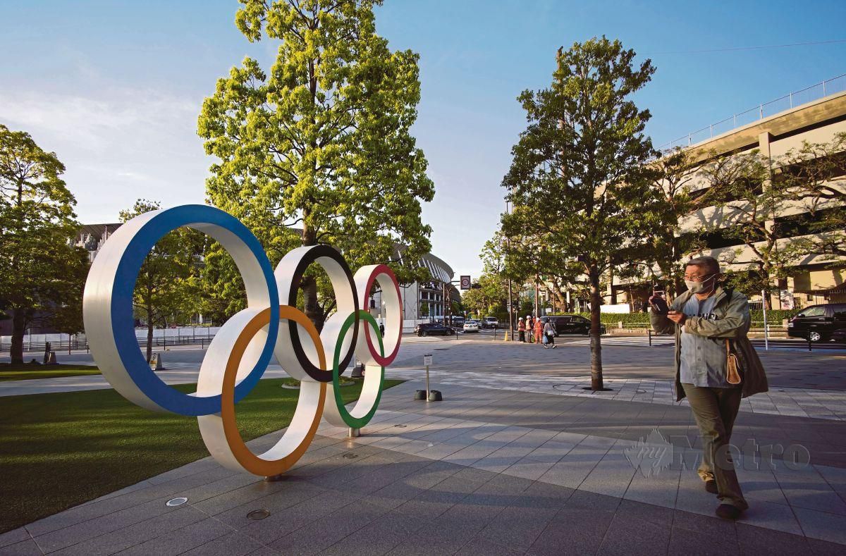 SEORANG lelaki merakam gambar logo Olimpik berhampiran Stadium Nasional di Tokyo. FOTO EPA
