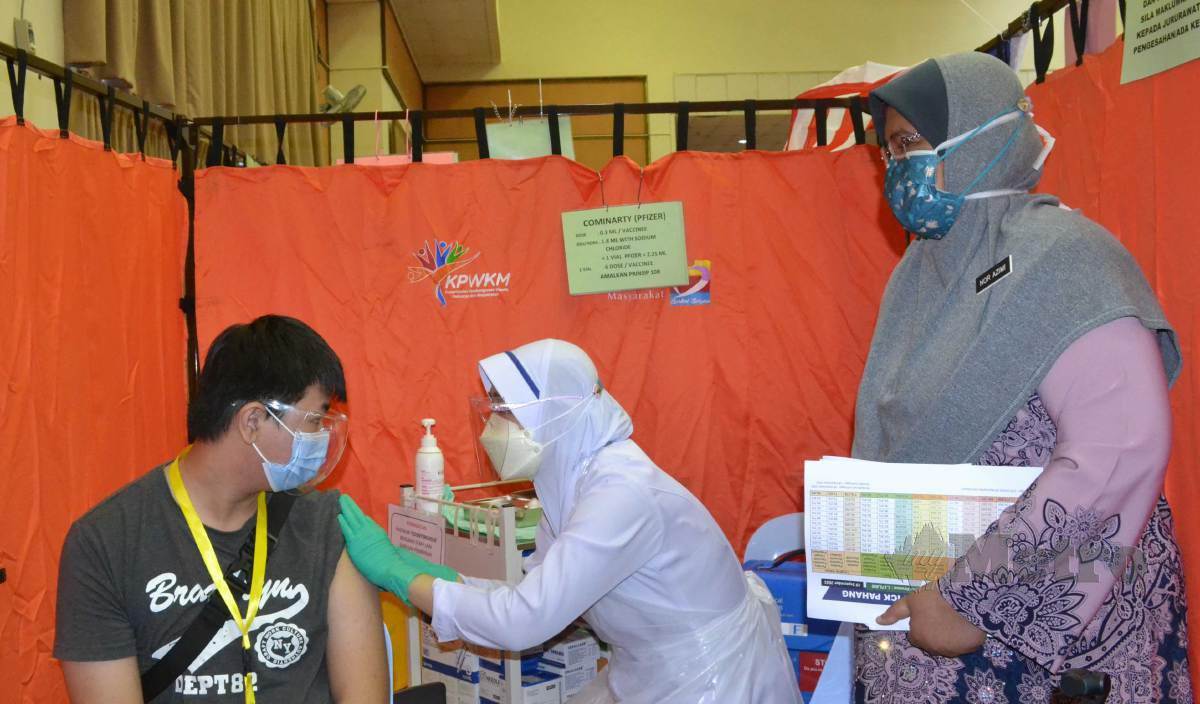DR Nor Azimi (kanan) melihat seorang pelajar menerima suntikan dos pertama pada Program Imunisasi Covid-19 Kebangsaan (PICK) Remaja di Wisma Belia, Kuantan. FOTO Asrol Awang