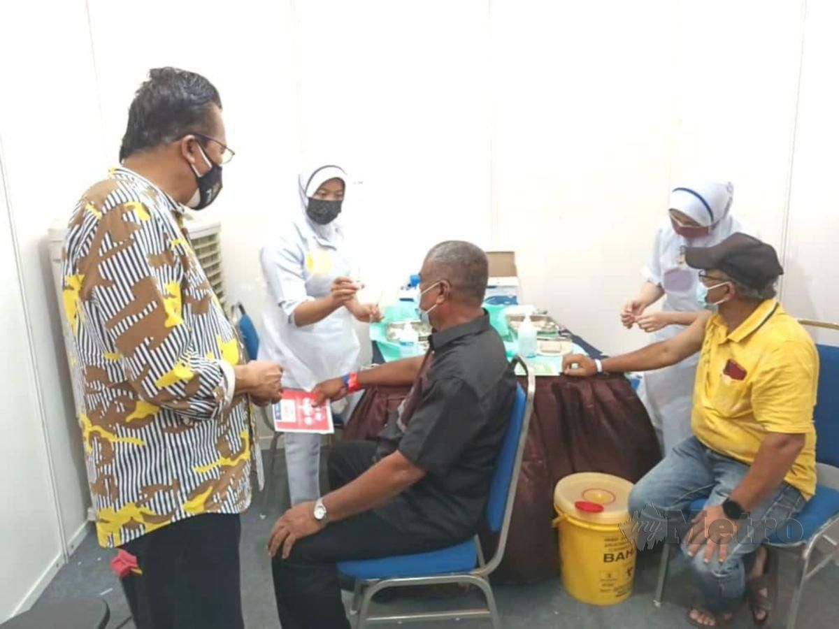 Mohd Salim (kiri) ketika meninjau  milik  pusat pemberian vaksin di Dewan Semai Bakti FELDA Serting Hilir Kompleks. FOTO ABNOR HAMIZAM