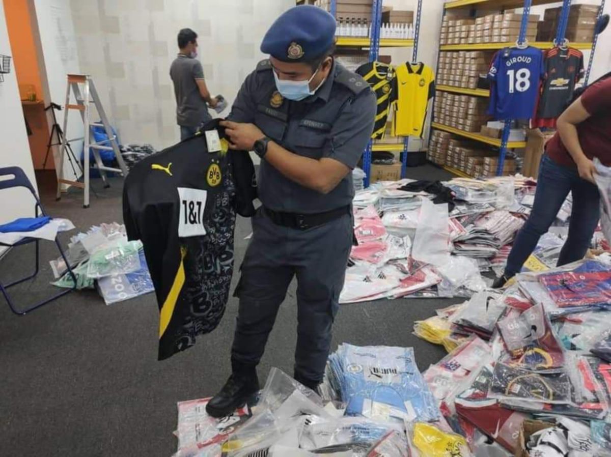 PEGAWAI KPDNHEP memeriksa jersi tiruan yang dirampas dalam serbuan di sebuah premis di Kepong semalam. 