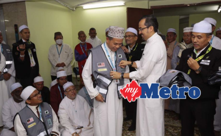 TIMBALAN Menteri di Jabatan Perdana Menteri, Datuk Dr Asyraf Wajdi Dusuki memakaikan 'vest' kepada Timbalan Mufti Sarawak Mual Suaud ketika melancarkan program Sahabat Maktab. IHSAN Tabung Haji