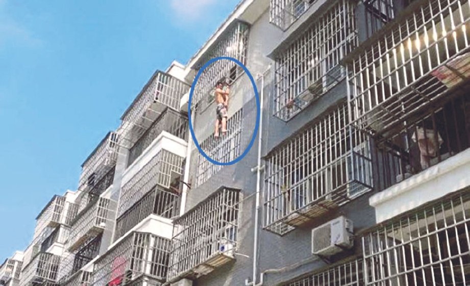GAMBAR menunjukkan Chen (dalam bulatan) memegang badan budak itu yang tersangkut di tingkat 4 sebuah apartmen di China pada Ahad lalu. - Agensi