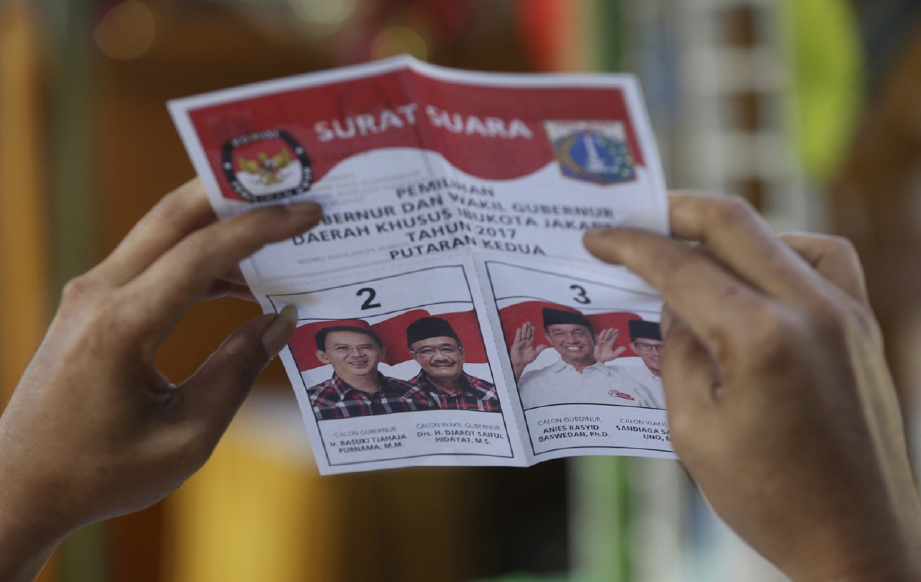 Pegawai pilihan raya memeriksa kertas undi ketika  Pilihan Raya Kepala Daerah (Pilkada) Jakarta, hari ini. - Foto AP 